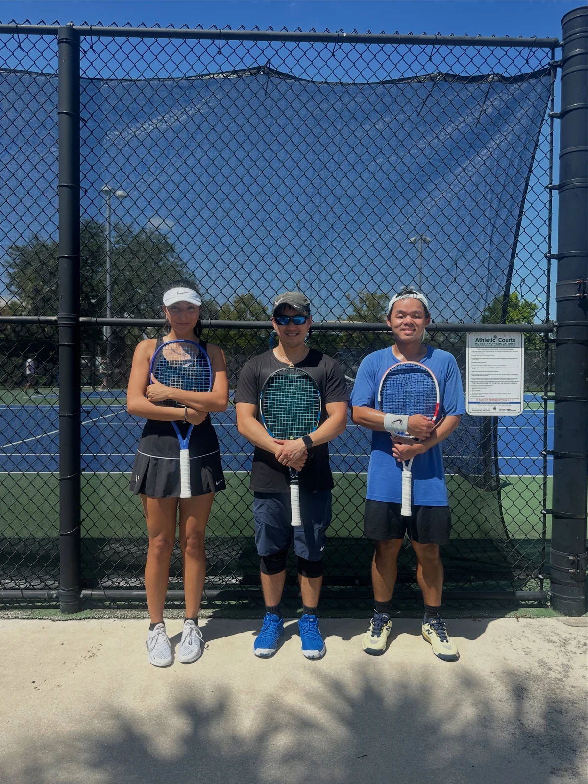Three Florida Tennis Partners players with their rackets beside the court